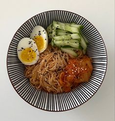 a bowl filled with noodles, cucumbers and hard boiled eggs on top of it