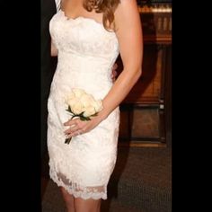 a woman in a white dress holding a bouquet of flowers and posing for the camera