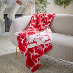 a red and white blanket sitting on top of a couch next to a fire place