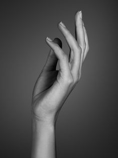 a person's hand with their fingers extended up in the air, against a gray background