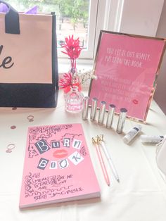 a table topped with pink notebooks and other personalized items next to a window