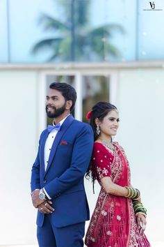 a man in a blue suit and tie standing next to a woman in a red dress