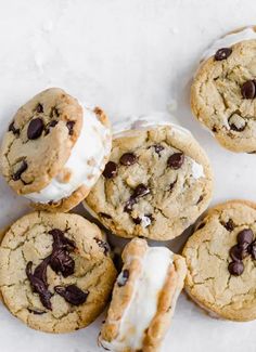 chocolate chip cookies with white frosting and sprinkles are arranged on a marble surface