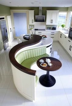 a kitchen with a curved counter top next to a breakfast nook in the center