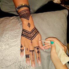 a woman's hand with henna tattoos on it