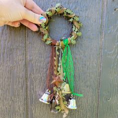 a hand is holding a wreath with bells attached to it