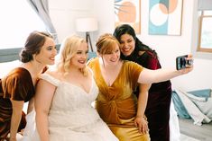 three women in dresses taking a selfie together