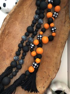 an orange and black beaded necklace with tassels on a piece of wood