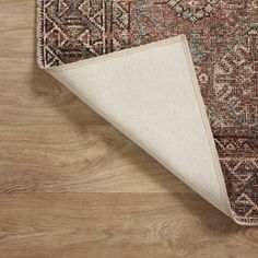 an area rug is laying on top of a wooden floor with a beige and brown color scheme