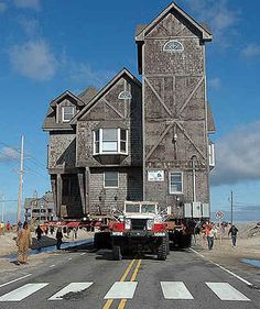 a truck is parked in front of an old wooden building with people walking around it