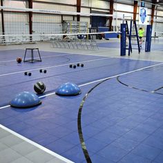 an indoor volleyball court with several blue balls on the floor