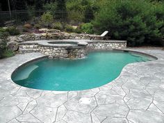 a small pool with a stone patio around it