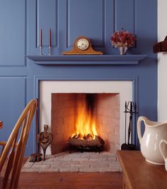 a fireplace with blue walls and a clock on the mantle