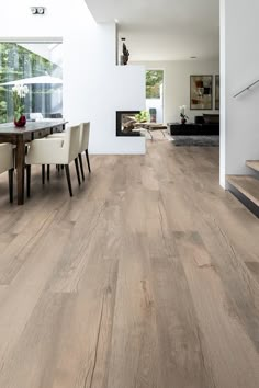 a dining room table and chairs with wood flooring in front of a white wall