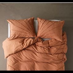 an orange comforter and pillows on a bed