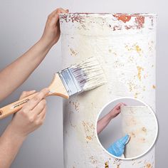 a person holding a paintbrush and painting the side of a white pillar with rust