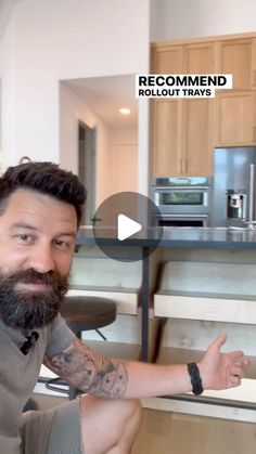 a man with a beard sitting in front of a kitchen counter