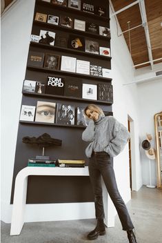 a woman leaning against a wall with books on it