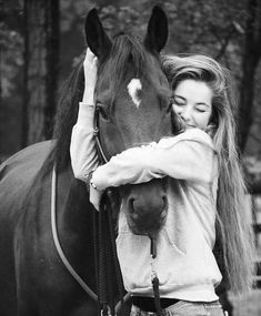 black and white photograph of a woman hugging a horse