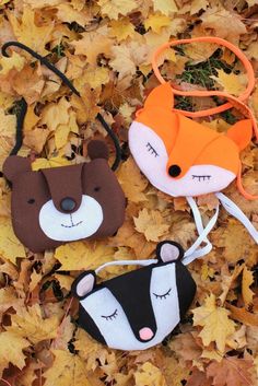 three small stuffed animals laying on top of leaves