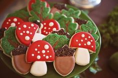 some cookies are on a green plate with red and white mushrooms in the grass next to broccoli