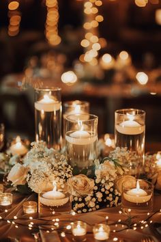 candles and flowers on a table with lights in the background