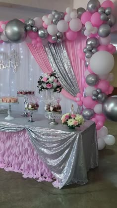 a table topped with lots of pink and silver balloons next to a cake stand filled with desserts