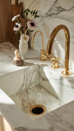 a marble sink with gold faucets and flowers