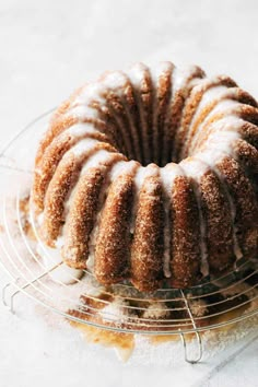 a bundt cake sitting on top of a wire rack covered in icing and powdered sugar