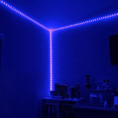 a room that has some lights on the ceiling and blue lighting in it, along with bookshelves