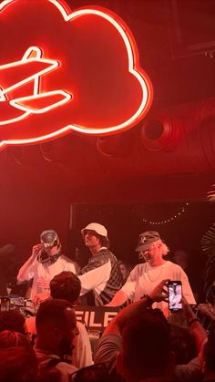 a group of men standing on top of a stage in front of a red neon sign