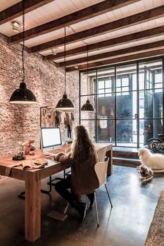 a woman sitting at a desk in front of a computer on top of a wooden table