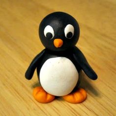 a small black and white penguin sitting on top of a wooden table