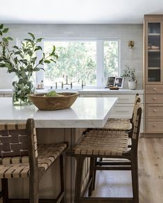 a kitchen with a bowl on the island next to two chairs in front of it