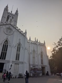 people are standing in front of a large white building with many windows and spires