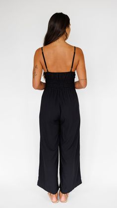 Stand out in this stunning jumpsuit, made to flow with buttery soft rayon and an exaggerated wide pant leg. Features adjustable straps and a gentle smocked waist to flatter. ** Our Model is 5'8" and wearing a size SMALL. ** Fabric & Care Instructions:100% RayonHand wash cold Line dry Chic Black Jumpsuits With Elastic Waistband, Black Jumpsuits And Rompers With Elastic Waistband For Spring, Casual Spaghetti Strap Jumpsuits And Rompers With Smocked Back, Black Elastic Waistband Jumpsuits For Spring, Black Sleeveless Jumpsuits With Smocked Back, Vacation Jumpsuit With Smocked Back And Spaghetti Straps, Chic Smocked Bodice Jumpsuits And Rompers For Brunch, Chic Maxi Length Jumpsuits And Rompers With Elastic Waistband, Black Smocked Bodice Jumpsuits And Rompers For Spring