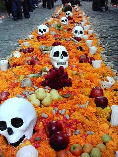 there are many skulls and apples on the street with orange flowers in front of them