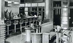 an old black and white photo of the inside of a restaurant with tables, chairs, and bar