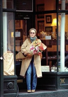 a woman walking out of a store holding flowers