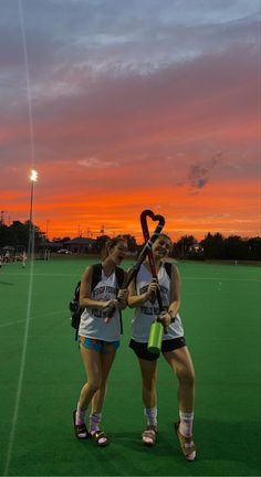 two female lacrosse players standing on the field at sunset