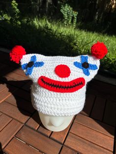 a crocheted hat with red, white and blue clown face on the front