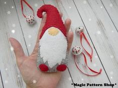 a hand holding a red and white felt santa clause ornament with bells on it