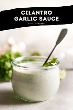 a small jar filled with white sauce and garnished with cilantro