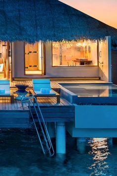 a house that is sitting on the water with a dock in front of it at night