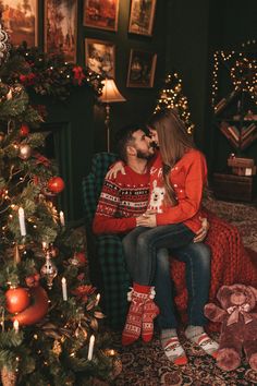 a man and woman sitting on a couch in front of a christmas tree