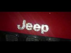 jeep logo on the side of a red car with chrome letters that spell out jeep