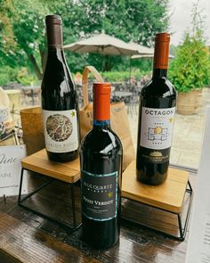 three bottles of wine sitting on top of a wooden table