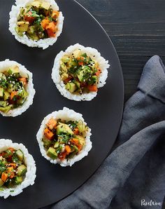 sushi on a black plate with chopsticks next to it and a napkin