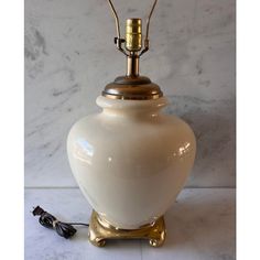 a white ceramic lamp with a gold base