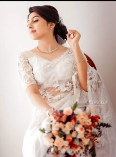 a woman in a white wedding dress holding a bridal bouquet with her eyes closed